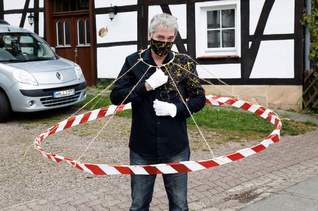 BODYART-Künstler Jörg Düsterwald in seinem Corona-Krisen-Outfit mit dem experimentellen Prototyp eines Abstandshalters. Würden alle Menschen solche Barrieren tragen, wären die notwendigen Distanzen gewahrt. Dazu trägt Düsterwald einen selbstgefertigten Mundschutz passend zum Hemd der eigenen, individuellen Mode-Kollektion aus seinem Projekt FASHION ART. Hameln, 02.05.2020
