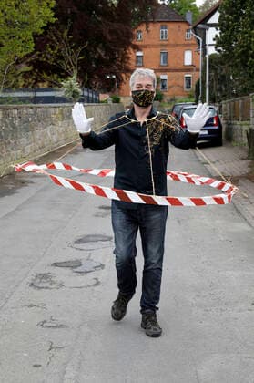 BODYART-Künstler Jörg Düsterwald in seinem Corona-Krisen-Outfit mit dem experimentellen Prototyp eines Abstandshalters. Würden alle Menschen solche Barrieren tragen, wären die notwendigen Distanzen gewahrt. Dazu trägt Düsterwald einen selbstgefertigten Mundschutz passend zum Hemd der eigenen, individuellen Mode-Kollektion aus seinem Projekt FASHION ART. Hameln, 02.05.2020