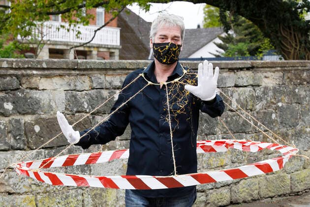 BODYART-Künstler Jörg Düsterwald in seinem Corona-Krisen-Outfit mit dem experimentellen Prototyp eines Abstandshalters. Würden alle Menschen solche Barrieren tragen, wären die notwendigen Distanzen gewahrt. Dazu trägt Düsterwald einen selbstgefertigten Mundschutz passend zum Hemd der eigenen, individuellen Mode-Kollektion aus seinem Projekt FASHION ART. Hameln, 02.05.2020