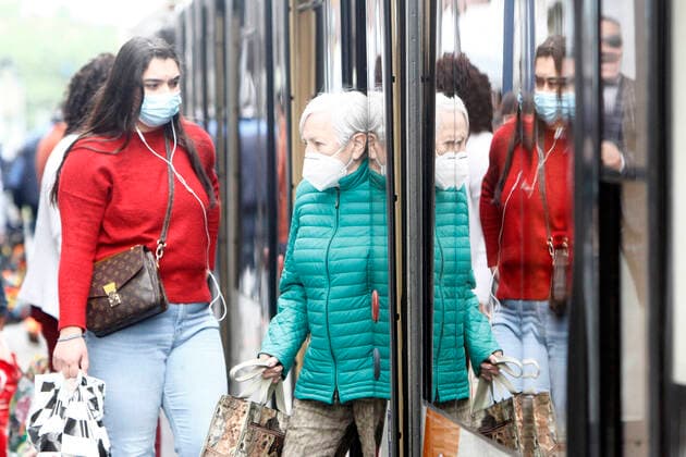 Fahrgäste mit Atemschutzmasken an einer Haltestelle mit Straßenbahn Zug des RNV Rhein Neckar Verkehrsverbund s in der Innenstadt Mannheim, Baden Württemberg, Deutschland