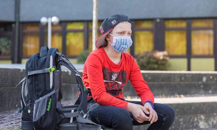 06.05.2020, Corona-Maßnahmen - Maskenpflicht und Schule Ein Junge mit einer Mund-Nasen-Behelfs-Maske sitzt auf dem Schulhof. Sieht so die neue Normalitaet unserer Kinder aus? Bad Brückenau Bayern Deutschland
