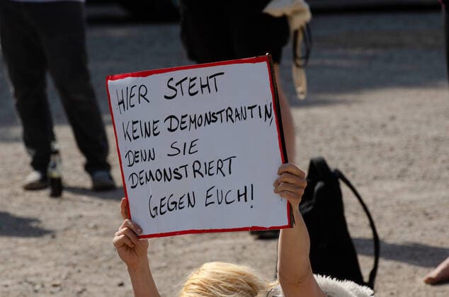 Coronavirus, Demonstration gegen Corona-Maßnahmen Demonstrantin hält Transparent mit der Aufschrift Hier steht keine Demonstrantin denn sie demonstriert gegen euch! , am 09.05.2020 in Flensburg, Hafen, Hafenspitze