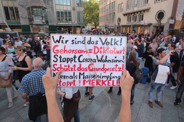 Eine genehmigte Demonstration gegen das coronabedingte Infektionsschutzgesetz und die damit einhergehenden Freiheitsbeschränkungen fand in der Innenstadt von Köln statt, Nordrhein Westfalen, Deutschland. Eine Demonstrantin hält ein Plakat mit Aufschrift wir sind das Volk, Gehorsam gleich Diktatur, stoppt Corona-Wahnsinn, schützt das Grundgesetz, niemas Massenimpfungen, stoppt Merkel.