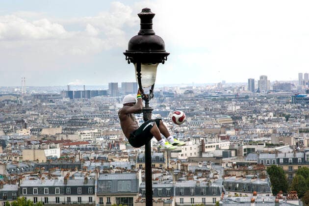 Freizeit Trend: Football Freestyle Fussballakrobat am Montmartre Paris, 21.09.14 - Iya Traoré, ein Akrobat jongliert mit einen Fussball an einem Laternenpfahl am Montmartre. Paris Frankreich Deutschland *** Football acrobat at Montmartre Paris, 21 09 14 Iya Traoré, an acrobat juggles with a football on a lamppost at Montmartre Paris France Germany