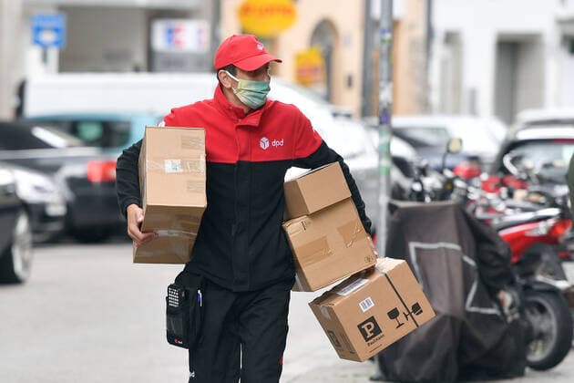 Wieder Heinsberg: Mindestens 42 Beschaeftigte eines Paketzustellers haben sich mit dem Coronavirus infiziert. Hunderte weitere werden nun getestet. Die Reproduktionsrate im Landkreis ist sehr hoch. Archivfoto: Oeffentliches Leben in Zeiten der Coronavirus Pandemie am 29.04.2020 in Muenchen. Ein Paketbote mit Mund-Nasenschutz, Mund-Nase-Maske, Mund-Nase Schutz, Maske, Masken traegt Pakete unter dem Arm. DPD Paketdienst,Zustellung.