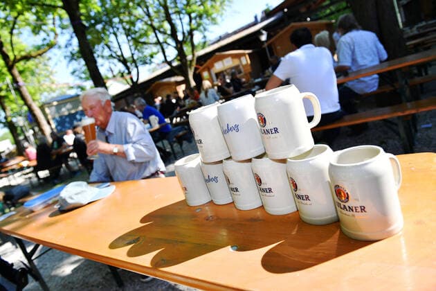 Bierkruege stehen auf einem Biertisch-im Hintergrund trinkt ein Mann ein Weissbier. Wiedereroeffnung Paulaner Biergarten am Nockherberg im Zuge der Corona Lockerungen am 18.05.2020 in Muenchen.