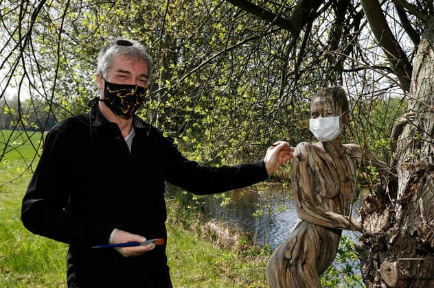 Nature Art Bodypainting mit Model Lisa als Teil eines Baumes an einem Fischeich. Beim Painten wurden Corona-Schutzmaßnahmen getroffen, Model und Künstler Jörg Düsterwald tragen Mundschutz. Springe, 18.05.2020