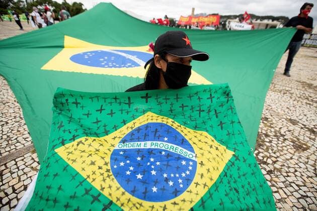 A woman holds a Brazilian flag with black crosses painted on to remember victims of covid-19, while participating in a protest against the President of Brazil, Jair Bolsonaro, at the Planalto Palace in Brasilia, Brazil, 20 May 2020. Convened by the members of the popular committee Bolsonaro Out , dozens of people participated in the demonstration that rejected Bolsonaro s statements and actions during the handling of the coronavirus crisis, which left more than 17,000 deaths in the South American country. Protest in Brasilia against Bolsonaro s actions in handling the pandemic !ACHTUNG: NUR REDAKTIONELLE NUTZUNG!  Copyright: xJoedsonxAlvesx AME1089 20200520-637255959487413609