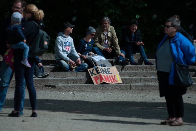 Coronavirus, Demonstration gegen Corona-Maßnahmen Vier Demonstranten sitzen auf Steinstufen, vor sich ein Transparent mit der Aufschrift Keine Panik , ein Demonstrant hat einen Judenstern auf der Jacke auf diesen steht Ungeimpft , am 23.05.2020 in Flensburg, am Hafen, Hafenspitze