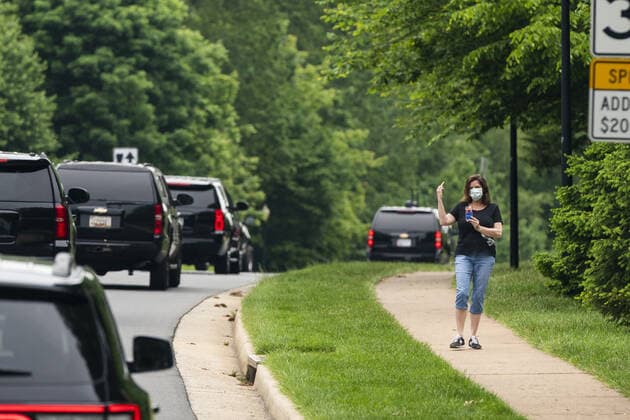 A woman expresses her displeasure to the motorcade ferrying President Donald Trump to the Trump National Golf Club in Sterling, Virginia, on Sunday, May 24, 2020. This is the second time in two days the president has visited his golf club near Washington, DC. He played golf on Saturday, the first time since the lockdown over the coronavirus COVID-19 pandemic. Nearly 100,000 Americans have died due to the novel virus.  WAX20200524107 JIMxLOxSCALZO