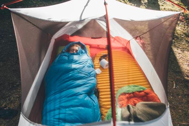 Young woman sleeping in sleeping bag in a tent model released Symbolfoto GUSF03701