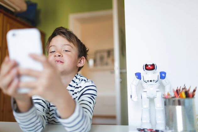 Boy doing homeschooling and using smartphone at home model released Symbolfoto property released HMEF00912