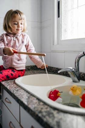 IMAGO Creative: Jahreszeit Winter, Fantasievoll drinnen spielen Portrait of little girl fishing rubber ducks in kitchen sink model released Symbolfoto property released JRFF04348
