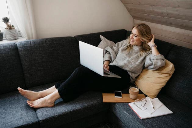 IMAGO Creative: Jahreszeit Winter, Couching Smiling woman using laptop on sofa while freelancing at home model released Symbolfoto property released LHPF01287