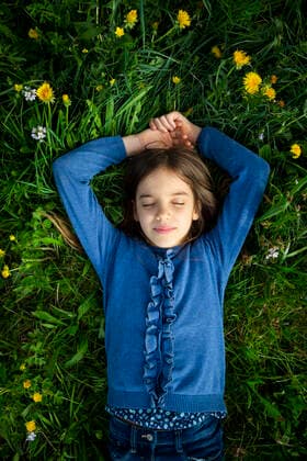 Portrait of girl with eyes closed relaxing on a meadow in spring model released Symbolfoto LVF08852