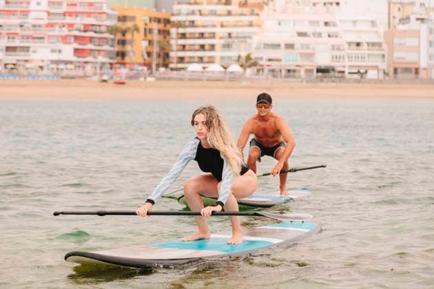 IMAGO Creative, Jahreszeit Sommer, Sommer in der Stadt Young woman practicing paddleboarding with instructor on sea model released Symbolfoto MRRF00033
