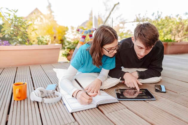 Teenage couple lying on terrace learning together with digital tablet model released Symbolfoto property released STDF00221