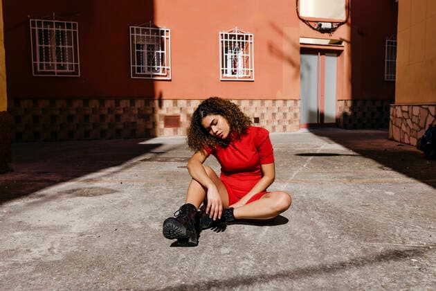 IMAGO Creative: Clickbait, Modetrends Young woman wearing red dress and sitting on ground model released Symbolfoto TCEF00499