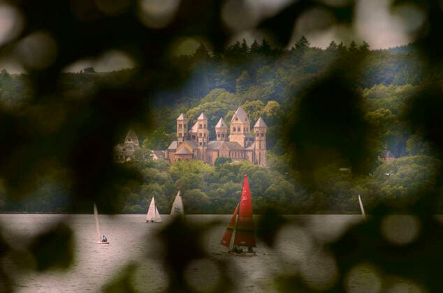 Die Abtei Maria Laach in der Eifel mit Segelbooten bei einer Regatta auf dem Laacher See