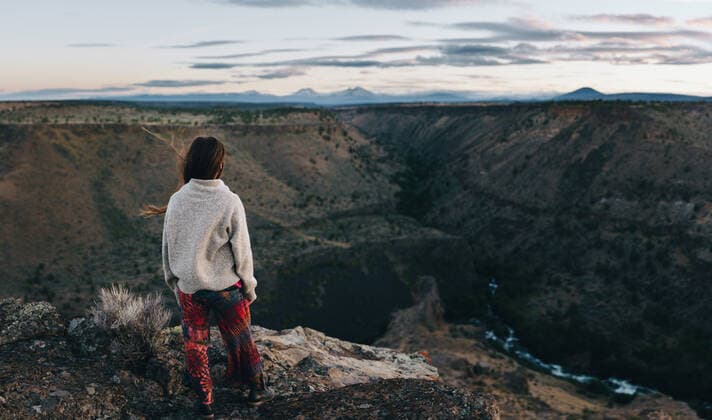 Young woman standing on cliff looking out over canyon at sunset Madras, OR, United States CR_ADMC200413-359485-01,model released, Symbolfoto