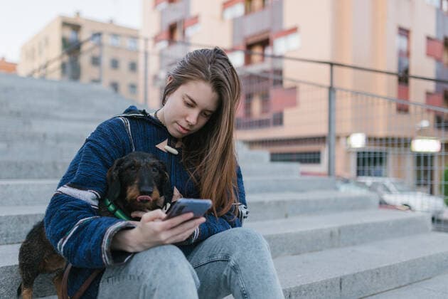 young adult woman looking her smartphone sit next to her dachshund dog Salamanca, CL, Spain CR_ALHE200515-400343-01,model released, Symbolfoto