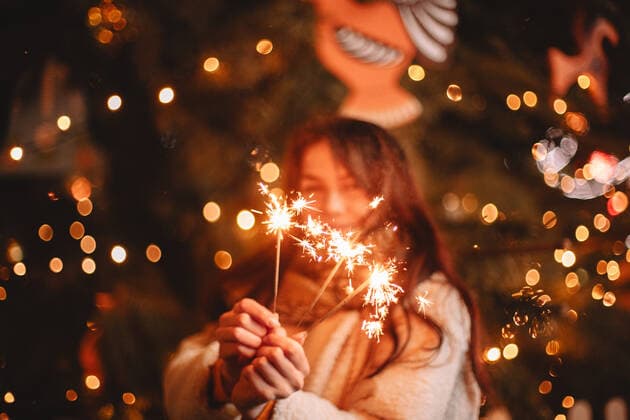 Teenage girl holding sparklers standing by luminous Christmas tree CR_DMBE200518-305164-01,model released, Symbolfoto