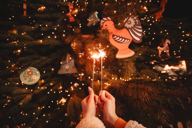 Female hands holding sparklers in front of luminous Christmas tree CR_DMBE200518-305186-01,model released, Symbolfoto