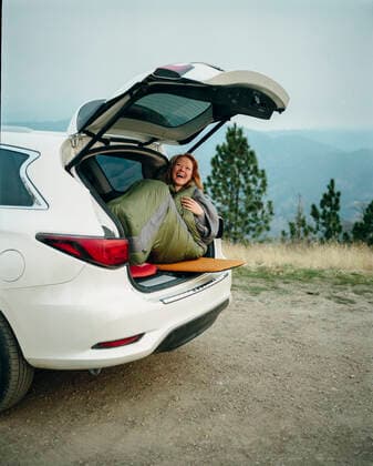Woman in sleeping bag laughing while car camping in Big Sur Big Sur, CA, United States CR_ISKO200402B-262876-01,model released, Symbolfoto