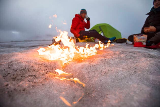 Campfire moves across the glacier as two men camp on a glacier. Pangnirtung, NU, Canada CR_JDIP200518-319539-01,model released, Symbolfoto