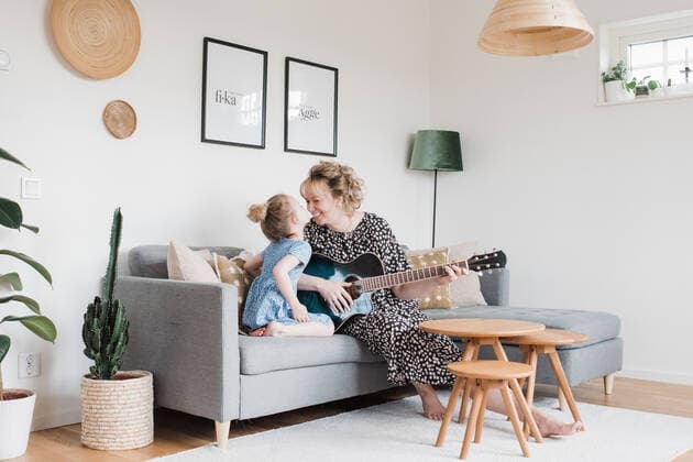 mother and daughter sat playing guitar together laughing at home Norrtälje, Stockholm County, Sweden CR_RABE200514-367333-01,model released, Symbolfoto