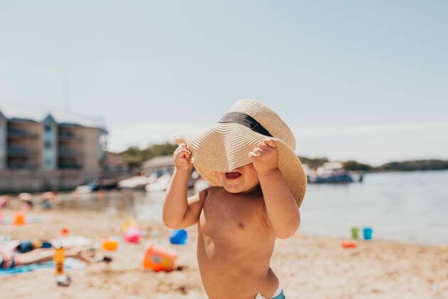 IMAGO Creative, Jahreszeit Sommer, Sonnenschutz Toddler Boy Playing Peek-a-boo with Sun Hat on Beach Milwaukee, WI, United States CR_SUWE200424C-371586-01,model released, Symbolfoto