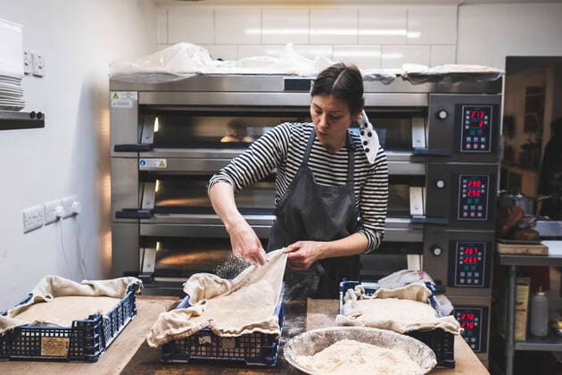 Artisan bakery making special sourdough bread, baker checking risen dough in plastic trays. United Kingdom,Artisan bakery making special sourdough bread, baker checking risen dough in plastic trays.  Artisan bakery making special sourdough bread, baker checking risen dough in plastic trays.