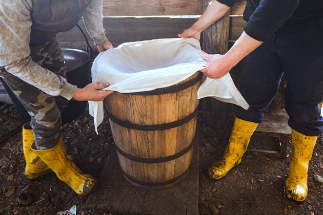 ZAKARPATIA REGION, UKRAINE - Men hold a gauze cloth over the barrel, Khust district, Zakarpattia Region, western Ukraine. Cheese making by shepherds of Zakarpattia Region  Copyright: xSerhiixHudakx