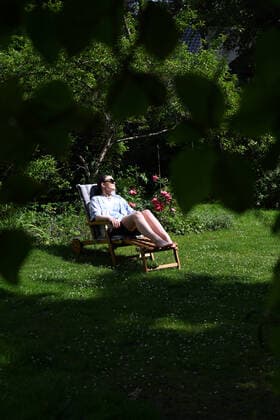 Junge Frau (model released) sonnt sich auf einer Gartenliege in einem Garten