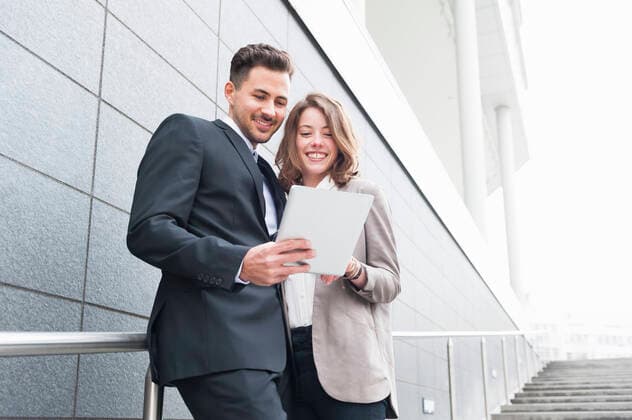 Happy business couple using digital tablet while standing on steps model released Symbolfoto DIGF12182
