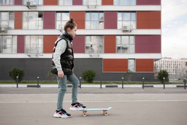 IMAGO Creative: Lokalhelden - Jugendsportbildung Girl with skateboard standing on road against building in city model released Symbolfoto EYAF01098
