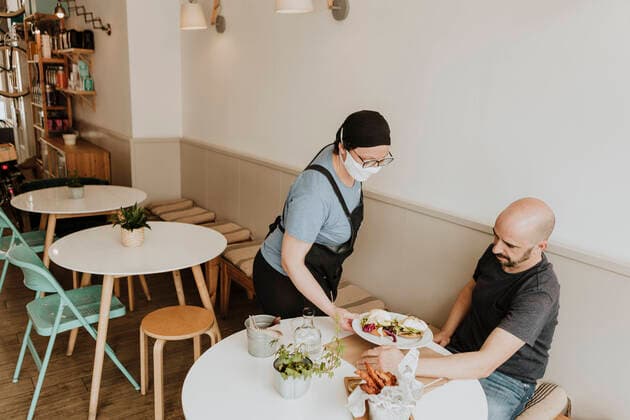 Waitress with protective mask serving food in a coffee shop model released Symbolfoto property released GMLF00231