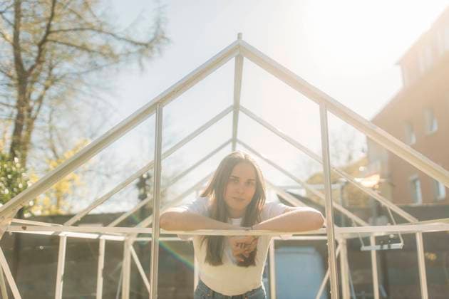 IMAGO Creative: Garten, Anbau im Gewächshaus Confident woman leaning on incomplete greenhouse during sunny day model released Symbolfoto property released GUSF03788