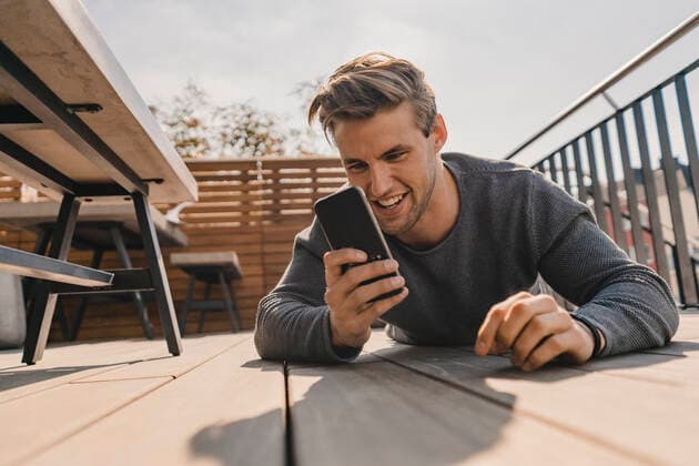Young man using smartphone on the bacony model released Symbolfoto property released KNSF08051