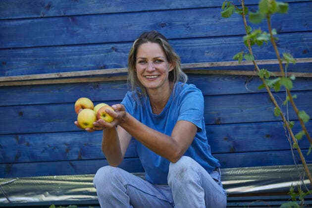 Portrait of smiling woman sitting at garden shed holding apples model released Symbolfoto property released MCF00904