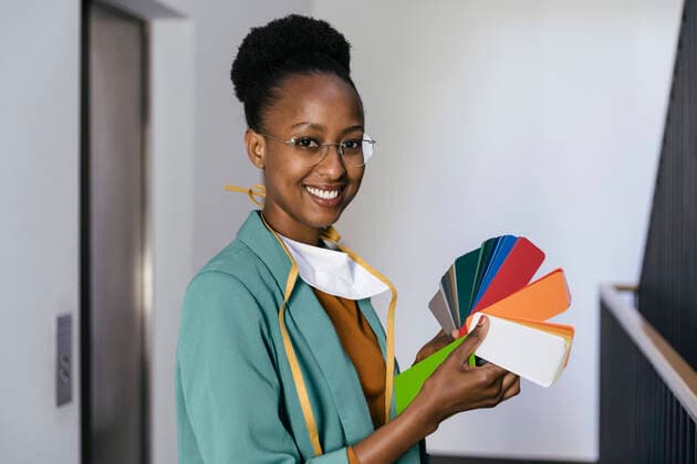 Portrait of smiling businesswoman with protective mask holding color sample in staircase model released Symbolfoto property released MFF05764