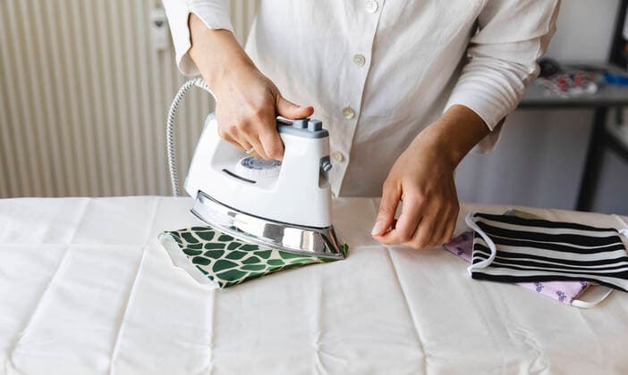 IMAGO Creative: Haushaltsgeräte, Bügeleisen Woman ironing homemade mask on board model released Symbolfoto MRAF00504
