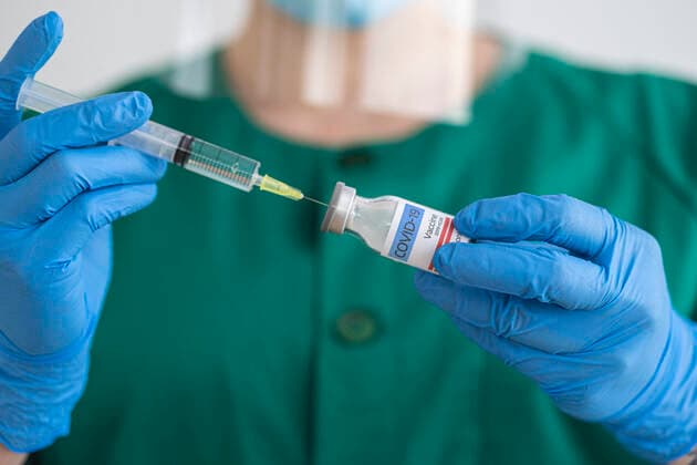 Woman in protective wear preparing covid-19 vaccination model released Symbolfoto SNF00123