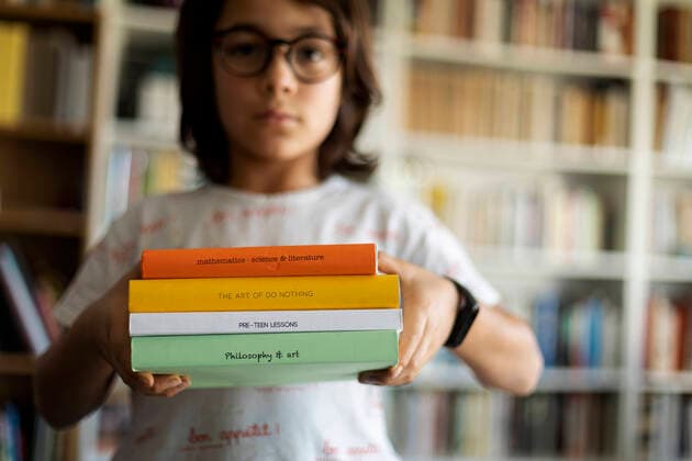 IMAGO Creative: NGO, Ausbildung für Kinder Boy holding stack of four books model released Symbolfoto property released VABF02949