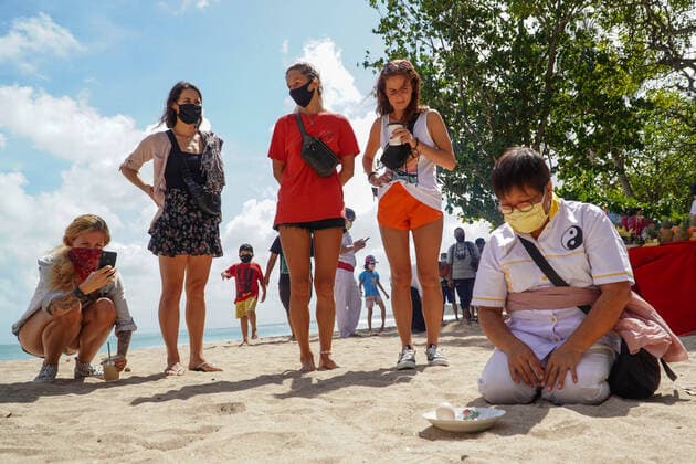 June 24, 2020, Badung, Bali, Indonesia: Tourists watching the rite s participant while make an egg stands as they believe the earth, the sun and the moon in a one straight line. Balinese Tionghoa ethnicity held Bak Cang prayers of Peh Cun rites at Kuta Beach as offerings to the God of the Sea amid Covid-19 coronavirus outbreak. Badung Indonesia - ZUMAb245 20200624_zip_b245_008 Copyright: xDickyxBisinglasix