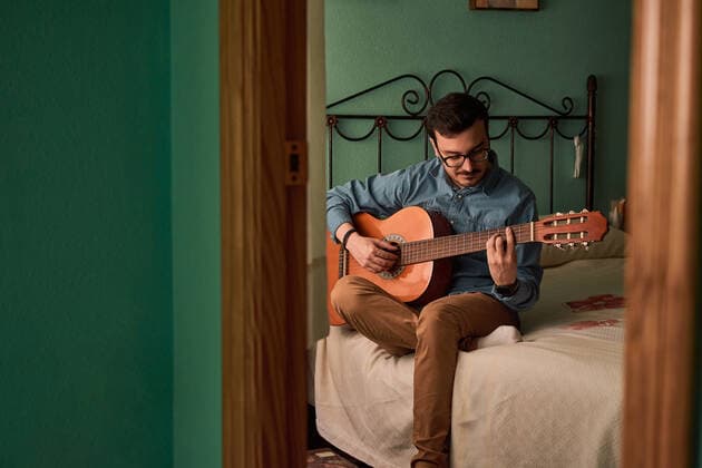 Young man plays guitar in a room in his house Villena, Valencian Community, Spain CR_CRBL200616-414345-01 ,model released, Symbolfoto