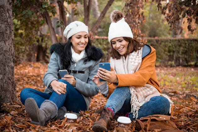 Two old girl friends looking at the smartphone screen together. Close up of Two old girl friends and the park background in the fall. Madrid, Community of Madrid, Spain CR_DAES200603-392887-01 ,model released, Symbolfoto