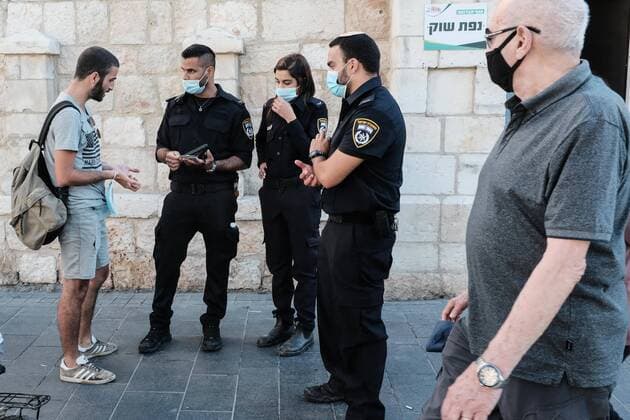 June 25, 2020, Jerusalem, Israel: Policemen detain and fine a young man not wearing a mandatory face mask in public. JerusalemÃ¢â‚¬â ¢s downtown area and popular Zion Square are flooded with young people seeking freedom as some Coronavirus restrictions eased in spite of an infection rate spike over recent weeks, in what some are calling a Ã¢â‚¬Ëœsecond waveÃ¢â‚¬â ¢. For the first time since the peak of the pandemic in April, the daily number of new COVID-19 cases exceeds 600, far surpassing a 100 Ã¢â‚¬Ëœred lineÃ¢â‚¬â ¢ defined by PM Netanyahu. Jerusalem Israel - ZUMAa126 20200625_zap_a126_002 Copyright: xNirxAlonx