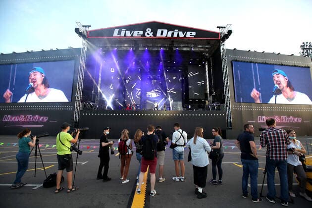 MOSCOW, RUSSIA - JULY 4, 2020: Journalists at a drive-in concert by The Hatters gypsy folk rock band in Luzhniki. The concert, in which the sound is broadcast to the cars via FM radio, is part of LIVE&DRIVE, a series of live drive-in concerts organised by the TCI concert agency and SAV Entertainment Group during the pandemic of the novel coronavirus disease (COVID-19). Vyacheslav Prokofyev TASS  TS0DF282