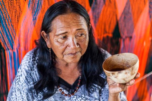 IMAGO Cultures of the world, Wayuu Volk in Kolumbien An elderly Wayuu woman drinking tinto or sweet black coffee from a calabash cup in front of her loom. Knitting, crocheting and weaving are fundamental to the social and economic lives of Wayuu women in La Guajira, Colombia. Uribia Colombia Copyright: xJasonxRothex JRO_COL-2